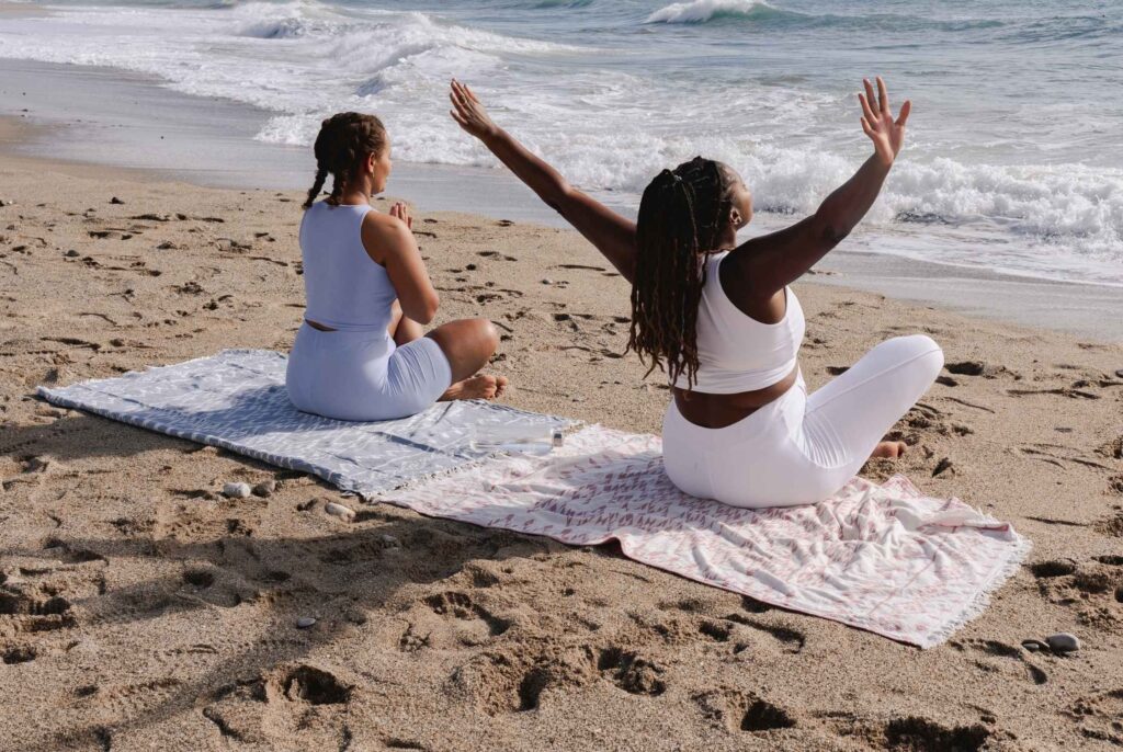 two women in perimenopause enjoying yoga by the ocean as self care