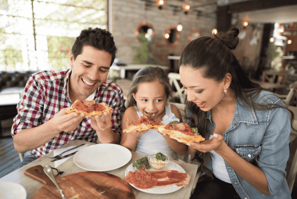 a child with food allergies enjoying a modified pizza with mom and dad
