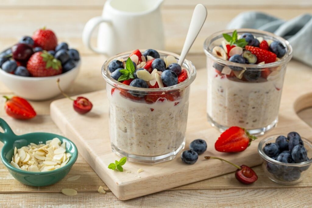 overnight oats in jars on a table topped with fruit and nuts/seeds