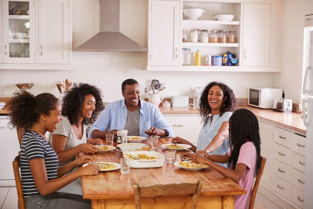 a family of busy teen athletes sitting down to eat a family dinner together