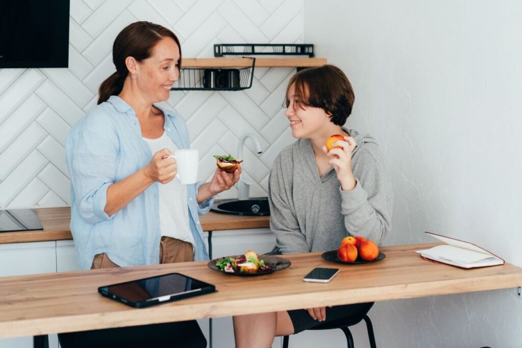 a mom and son smile at each other while meal prepping for a busy week of sports