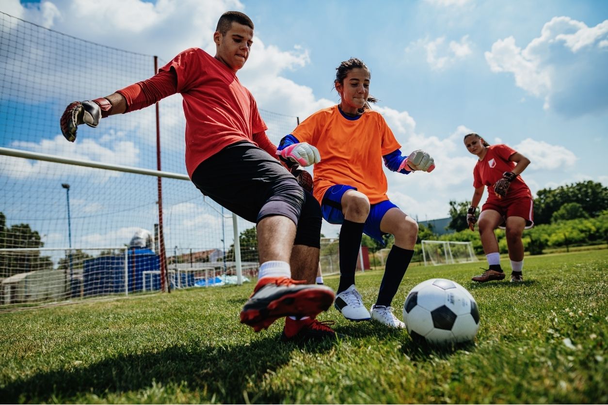 close up of teens and tweens playing soccer outdoors in the grass