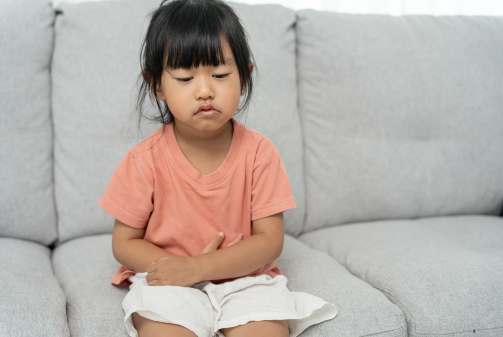 a small child clutching her stomach in pain because constipation in kids is painful
