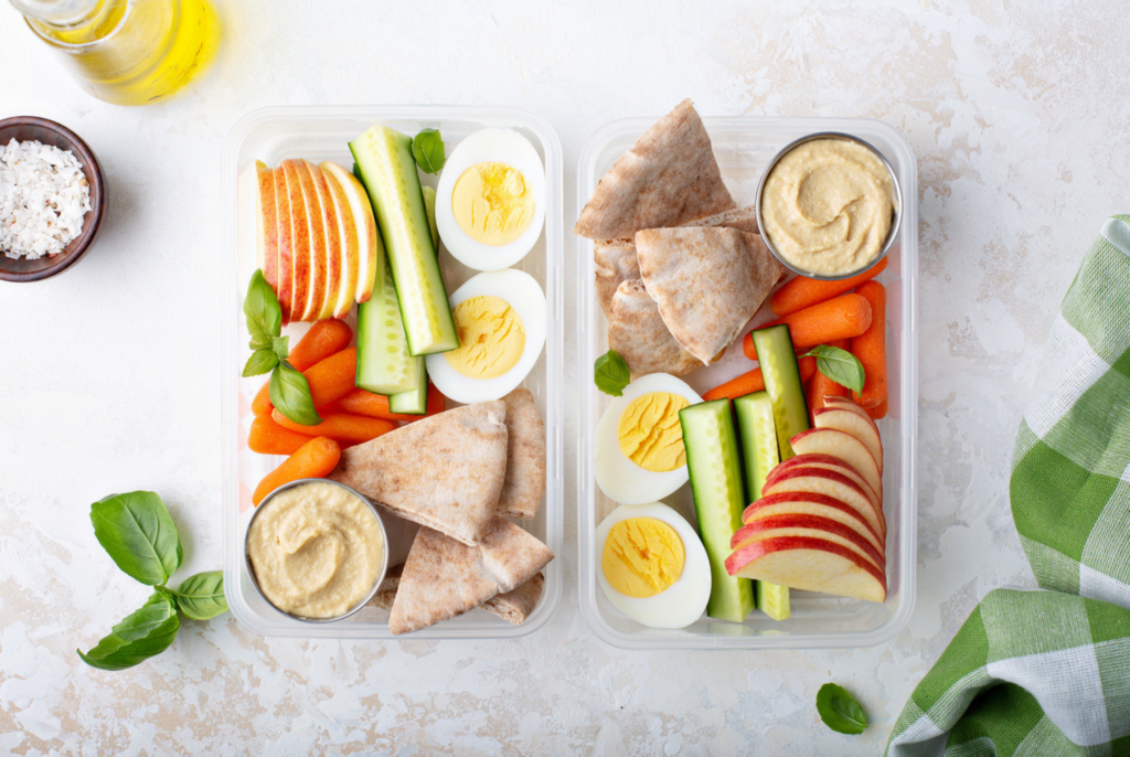 top down view of simple summer lunches for picky eaters including pita breads with sliced veggies and boiled eggs and hummus