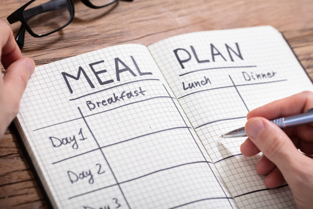 a person writing in a meal planner